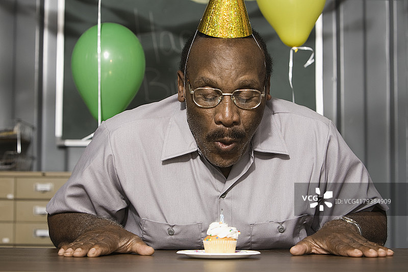 年长非裔美国男性工人正在吹生日蜡烛图片素材