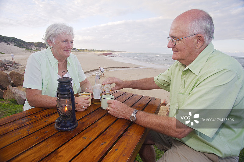 老年夫妇用传统非洲锡制马克杯小酌，南非东开普省杰弗里湾图片素材