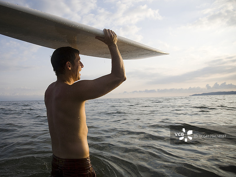 在水中拿着冲浪板的男人图片素材