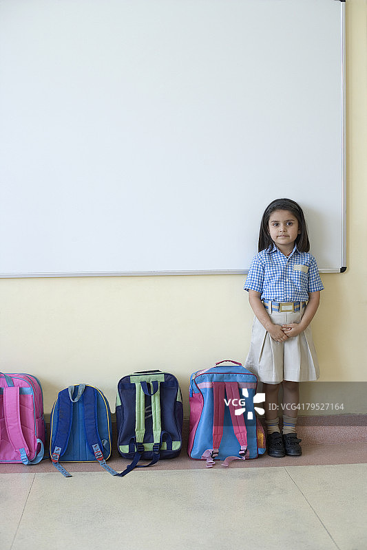 教室里站在书包旁的女学生肖像图片素材