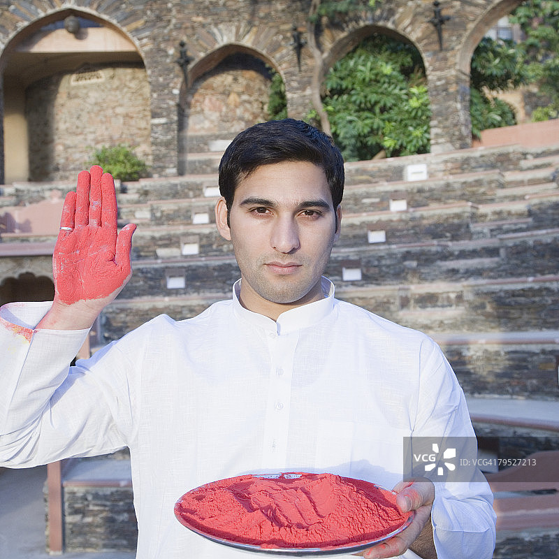 拿着一盘粉末颜料并展示手掌的年轻男人肖像，尼姆拉纳堡宫，印度拉贾斯坦邦阿尔瓦尔图片素材