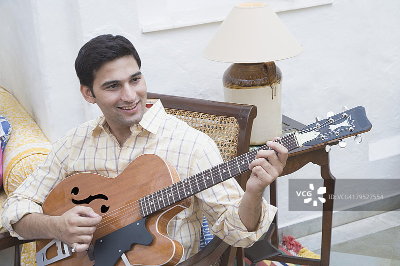 年轻男子弹吉他并微笑图片素材
