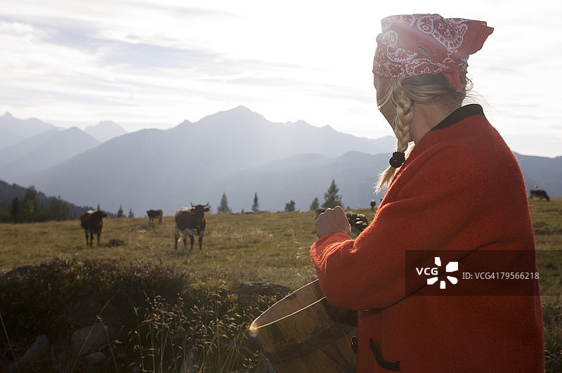 手捧黄油罐，背景是奶牛的女人图片素材