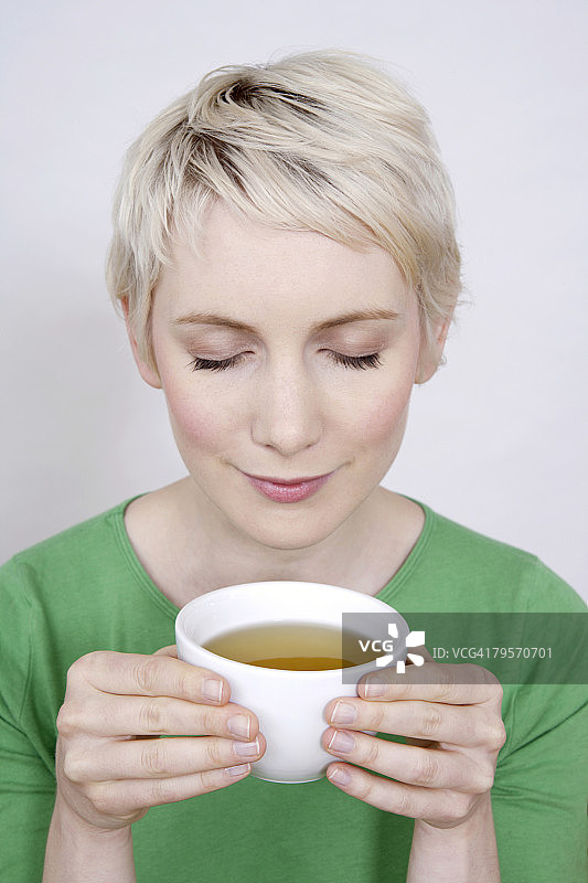 年轻女子手持茶碗的肖像图片素材