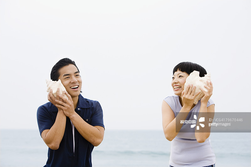 亚洲夫妇听海螺壳图片素材