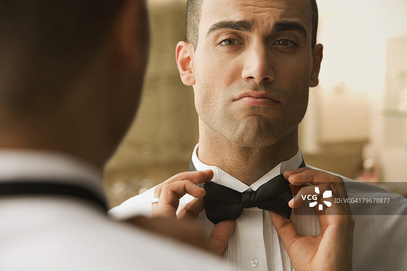 正在整理领结的西班牙裔男人图片素材