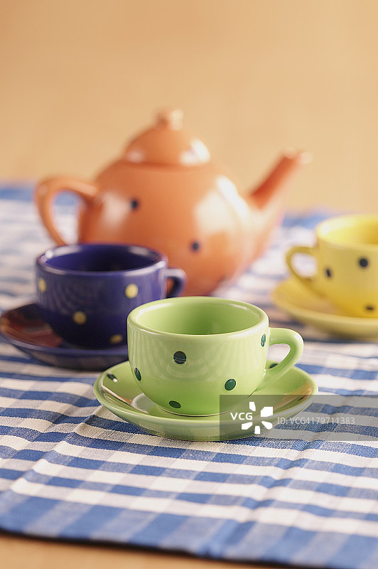 格子桌布上的茶壶、杯子和茶托图片素材