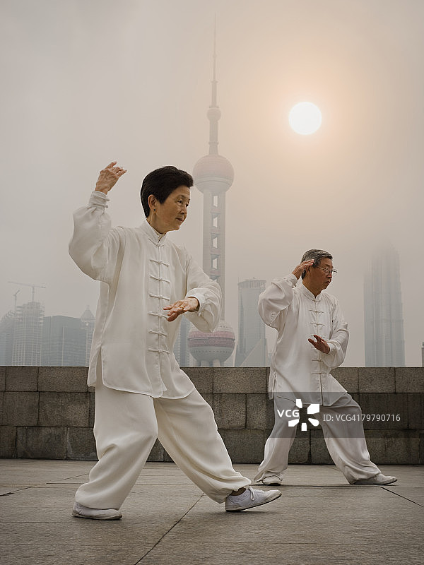 情侣在户外打太极，城市天际线背景图片素材