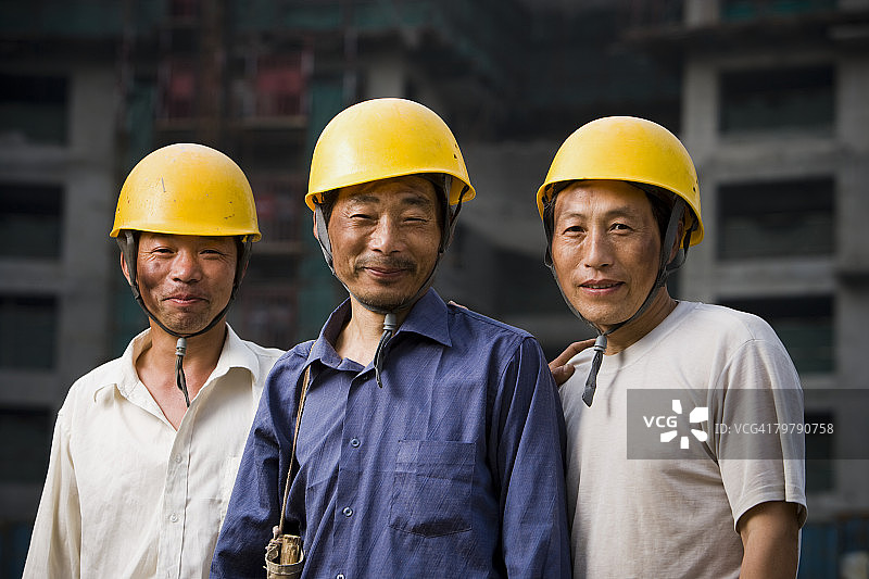 户外微笑的三名戴头盔的男性建筑工人图片素材