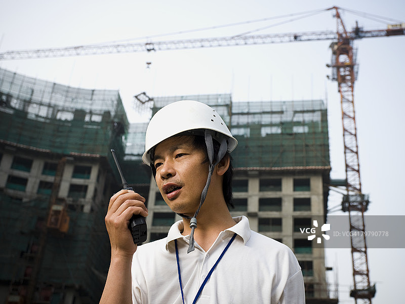 戴着建筑头盔和起重机的人拿着对讲机图片素材