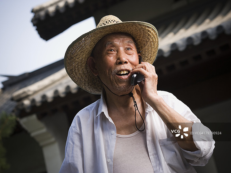 在户外微笑着用手机交谈的中年男人图片素材