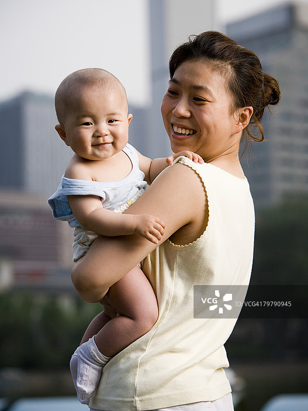 在户外微笑地抱着婴儿的女人图片素材