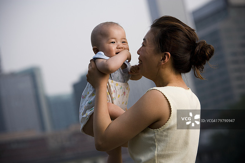 在户外微笑地抱着婴儿的女人图片素材