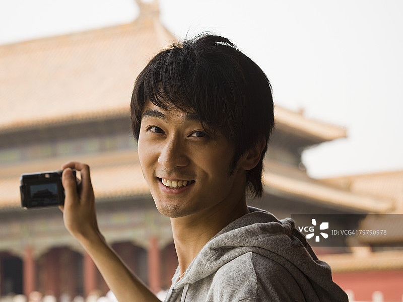 户外拿着数码相机微笑的青少年男孩图片素材