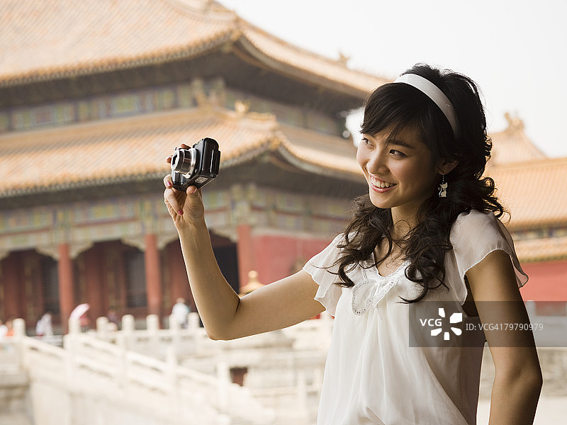 在户外以宝塔为背景拍照的少女图片素材