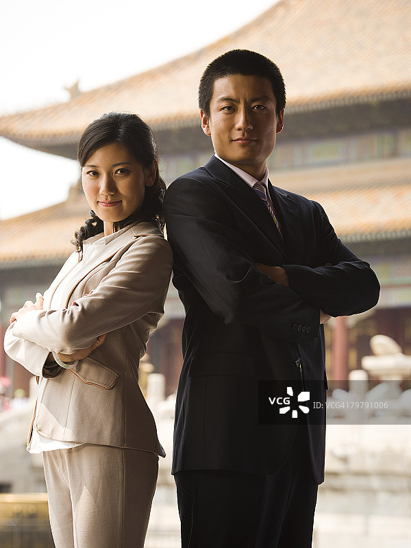 商人和女人背靠背站立，双手交叉，背景是宝塔图片素材