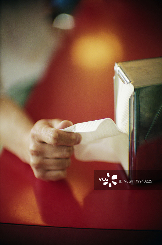 手从分配器中抽取餐巾纸图片素材