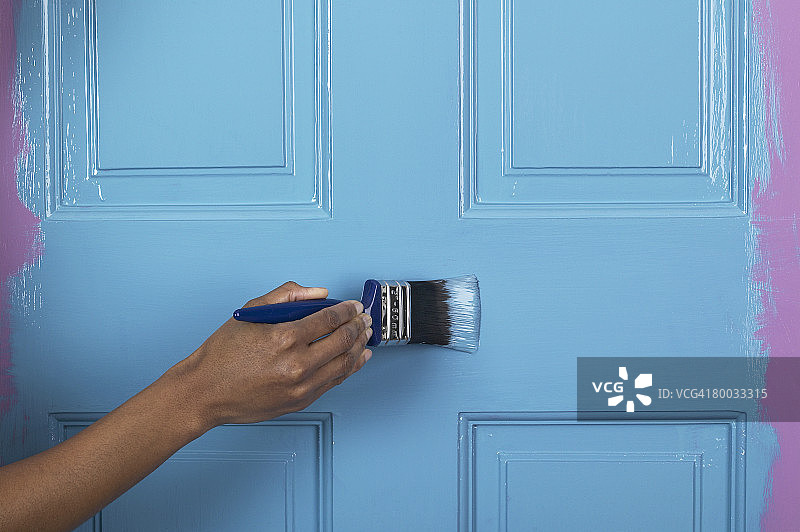 用刷子给门刷蓝色油漆图片素材