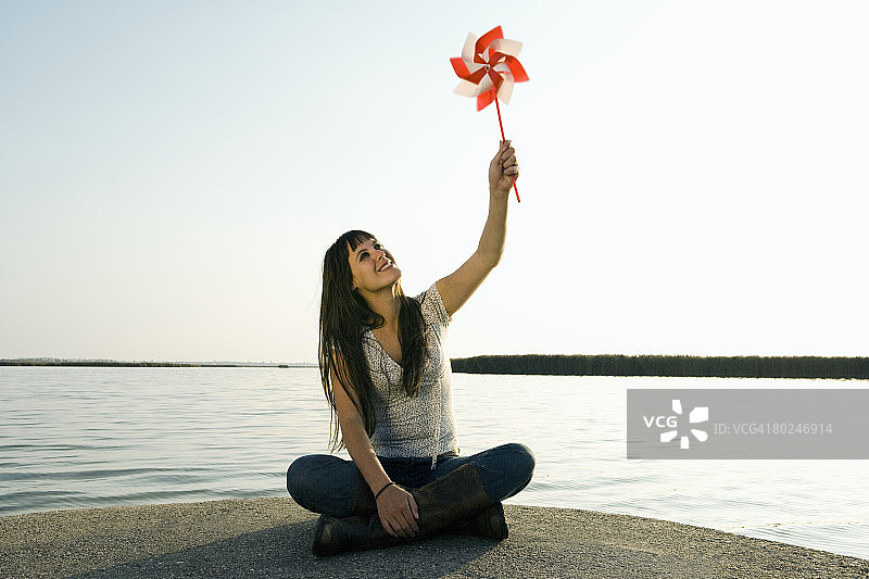 女人将玩具风车举向空中图片素材