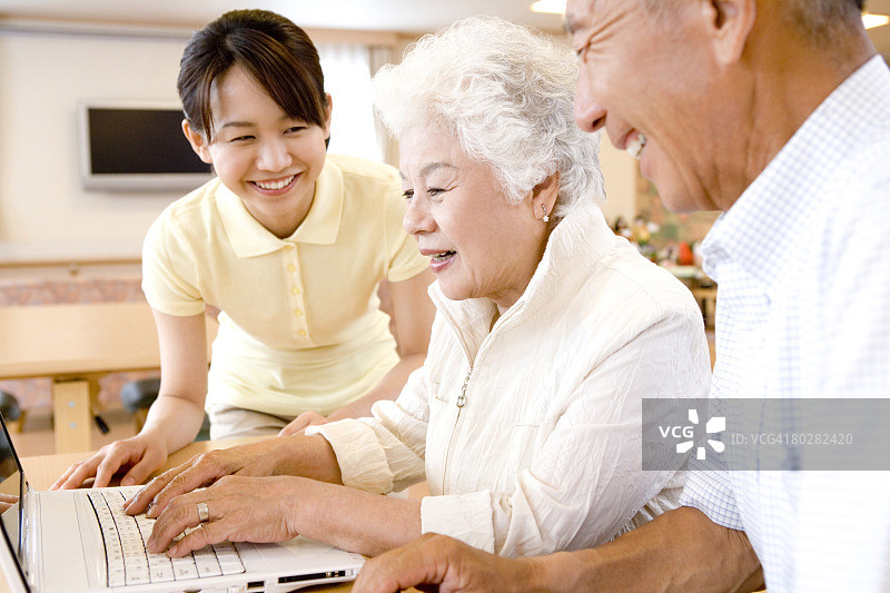 老年夫妇和护士一起看笔记本电脑，微笑图片素材