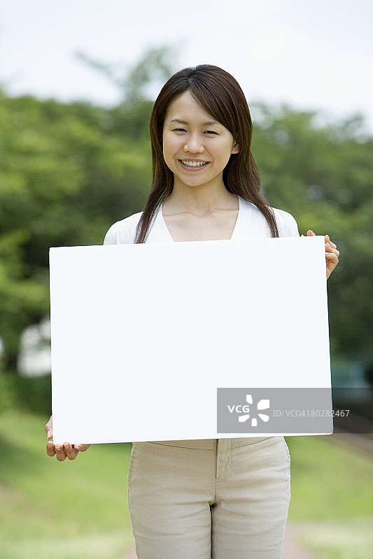 年轻女子手持空白板肖像照，焦点偏移图片素材