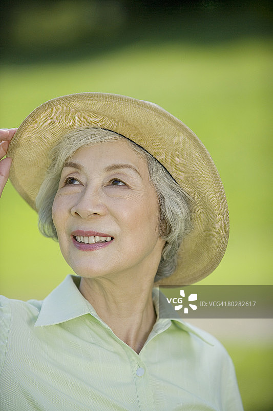 戴着帽子向上看的微笑年长女性图片素材