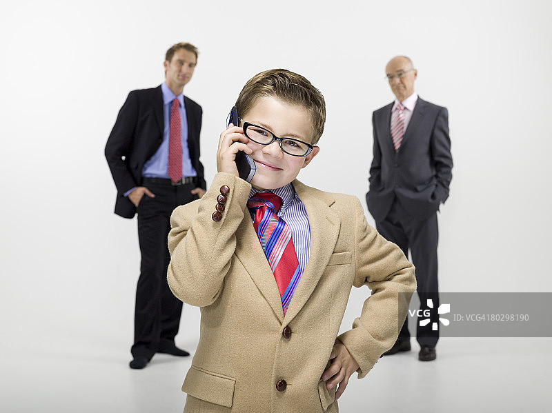 8-9岁孙子使用手机，祖父和儿子在背景中，肖像图片素材