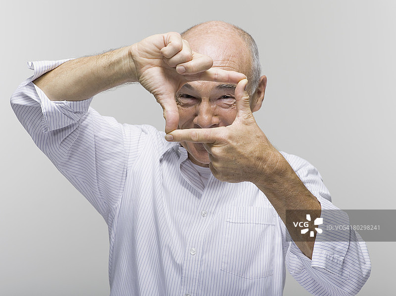 用一只手在另一只手上做手势的年长男人肖像图片素材