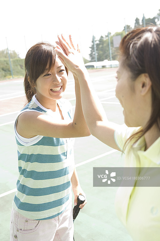 两位年轻女子在网球场上击掌图片素材
