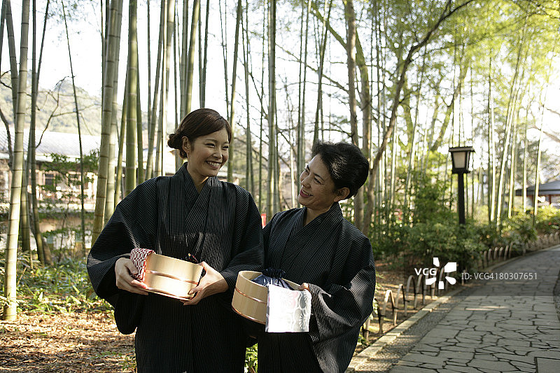老年妇女和年轻女子在花园里散步，提着水桶图片素材