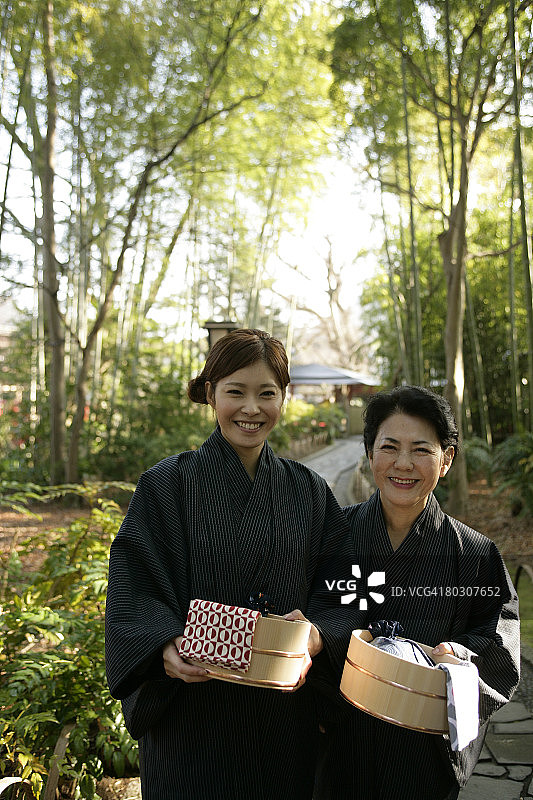 站在花园里，提着水桶的中年妇女和年轻女子图片素材