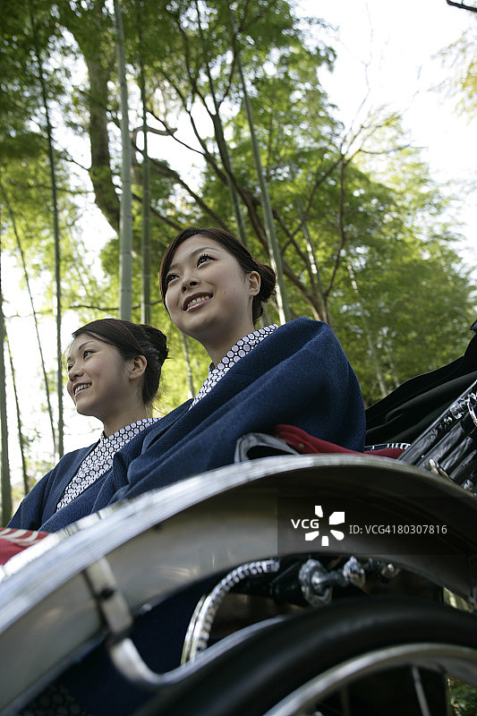 两名女子坐在人力车上，低角度拍摄图片素材
