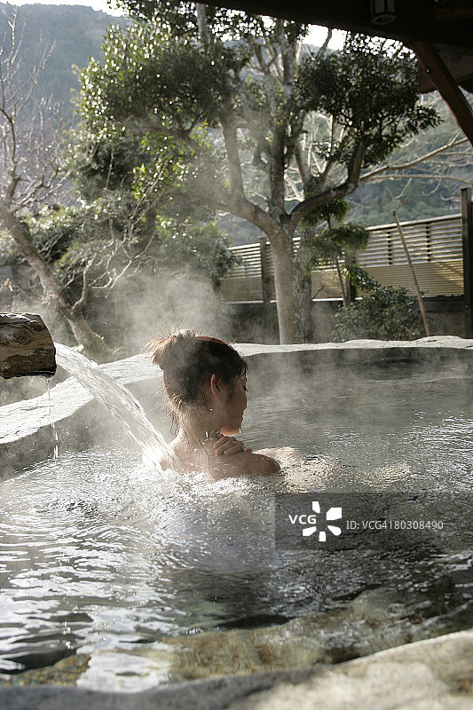 女人泡在热水浴缸里，水从背上流下来图片素材