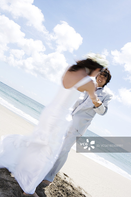 海滩上牵手的新娘和新郎图片素材