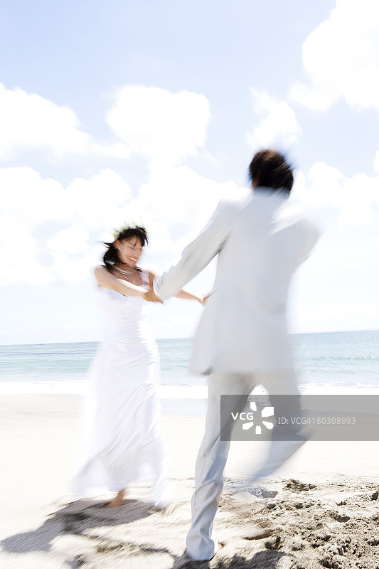 海滩上牵手的新娘和新郎图片素材