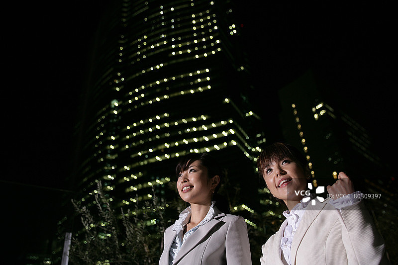 两位女性在夜晚的街道上行走，特写，低角度图片素材
