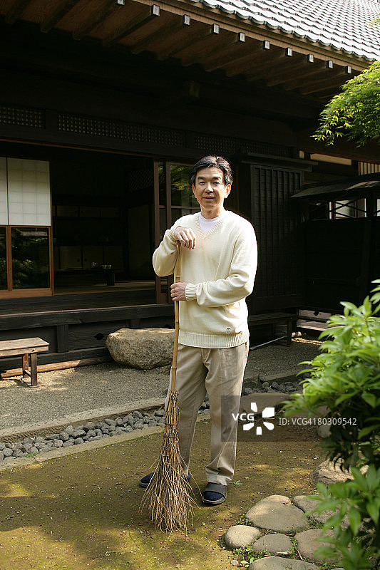 在庭院里拿着扫帚的中年男人图片素材