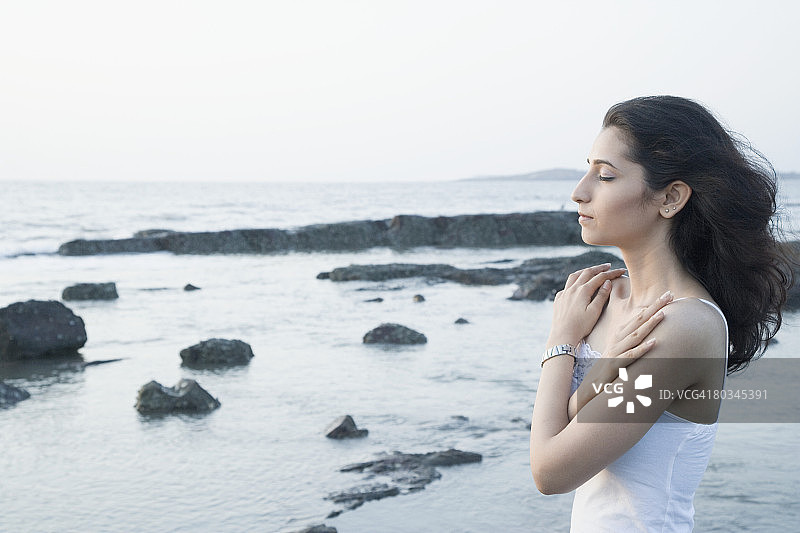 年轻女人海岸边拥抱自己侧面图片素材
