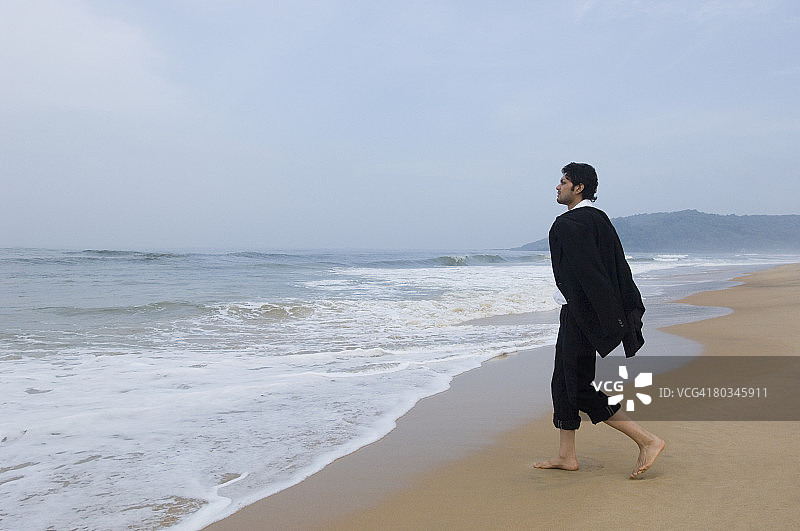 走在海滩上的商务人士的侧面轮廓图片素材