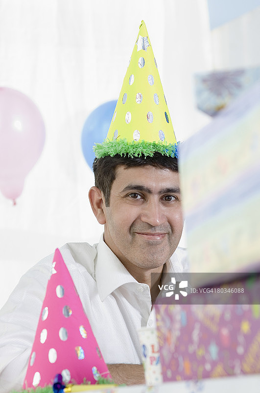 中年男人戴着生日帽微笑图片素材