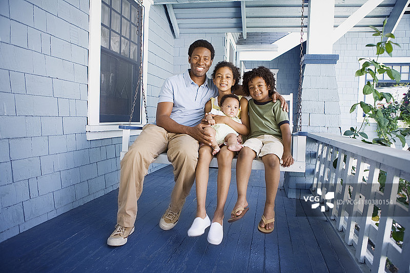 父亲和孩子们坐在门廊秋千上图片素材