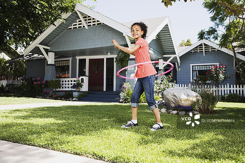 在房子草坪上玩塑料圈玩具的女孩图片素材