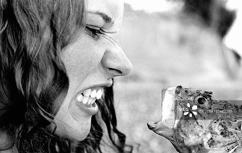 年轻女人紧咬着鱼，特写图片素材