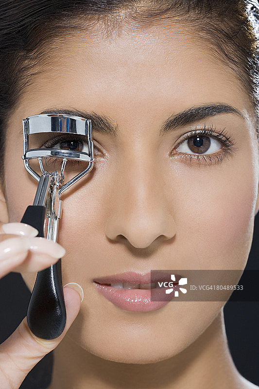 一位正在卷睫毛的女人图片素材