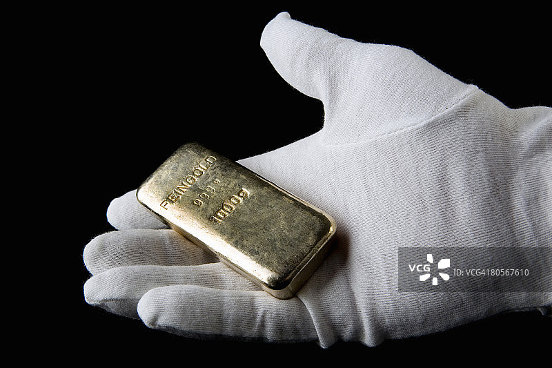 戴手套的手拿着金条图片素材