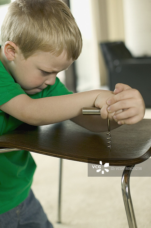 男孩用开瓶器拧椅子图片素材