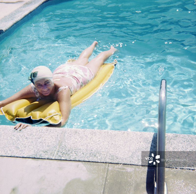 女人躺在泳池里的充气床垫上图片素材