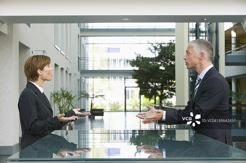 在接待处与女员工交谈的年长商人图片素材