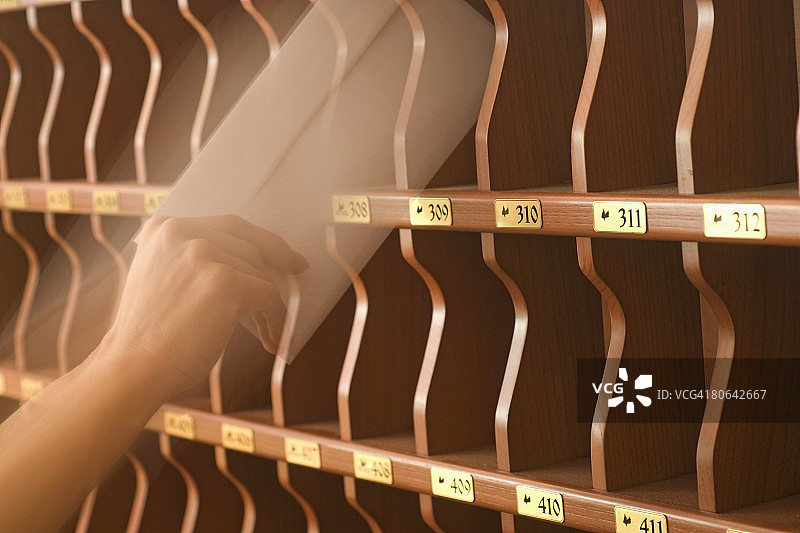 手将信件放入酒店接待处的鸽子笼中图片素材