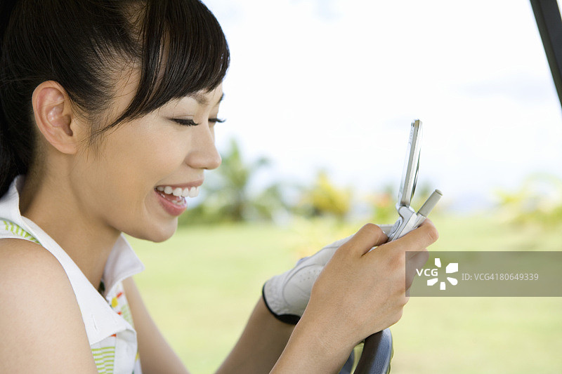 在球童车上拿着手机的年轻女人图片素材